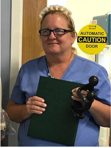 awardee wearing a headband of daisies, daisy award statue, and certificate.