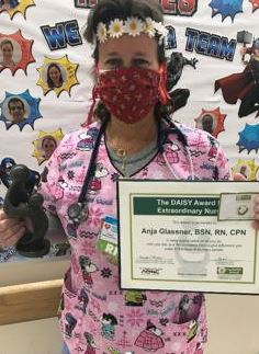 awardee wearing a headband of daisies, daisy award statue, and certificate.