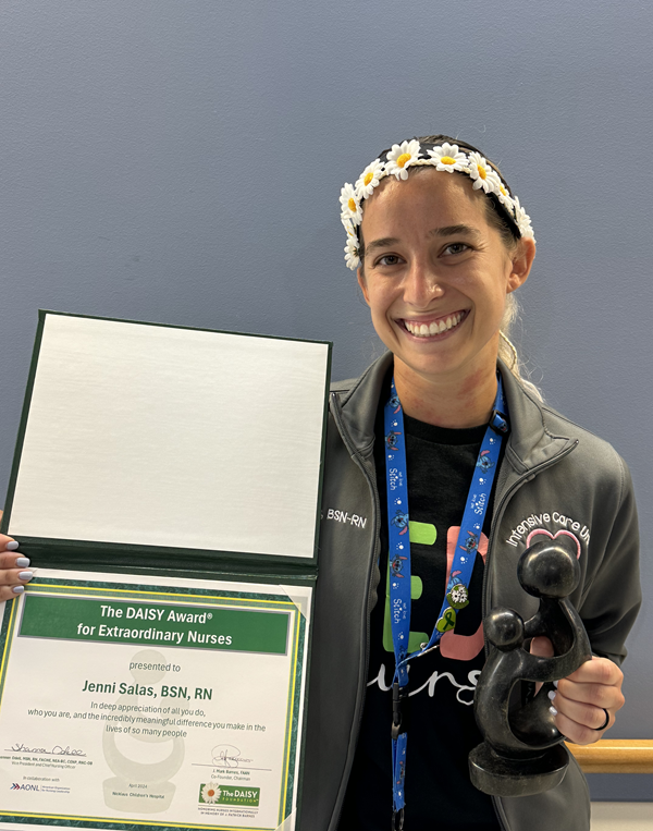 awardee wearing a headband of daisies, daisy award statue, and certificate.