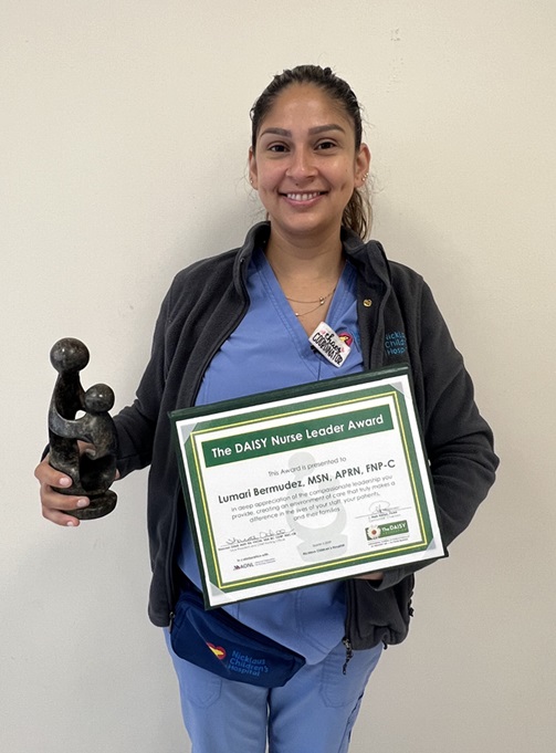 awardee wearing a headband of daisies, daisy award statue, and certificate.