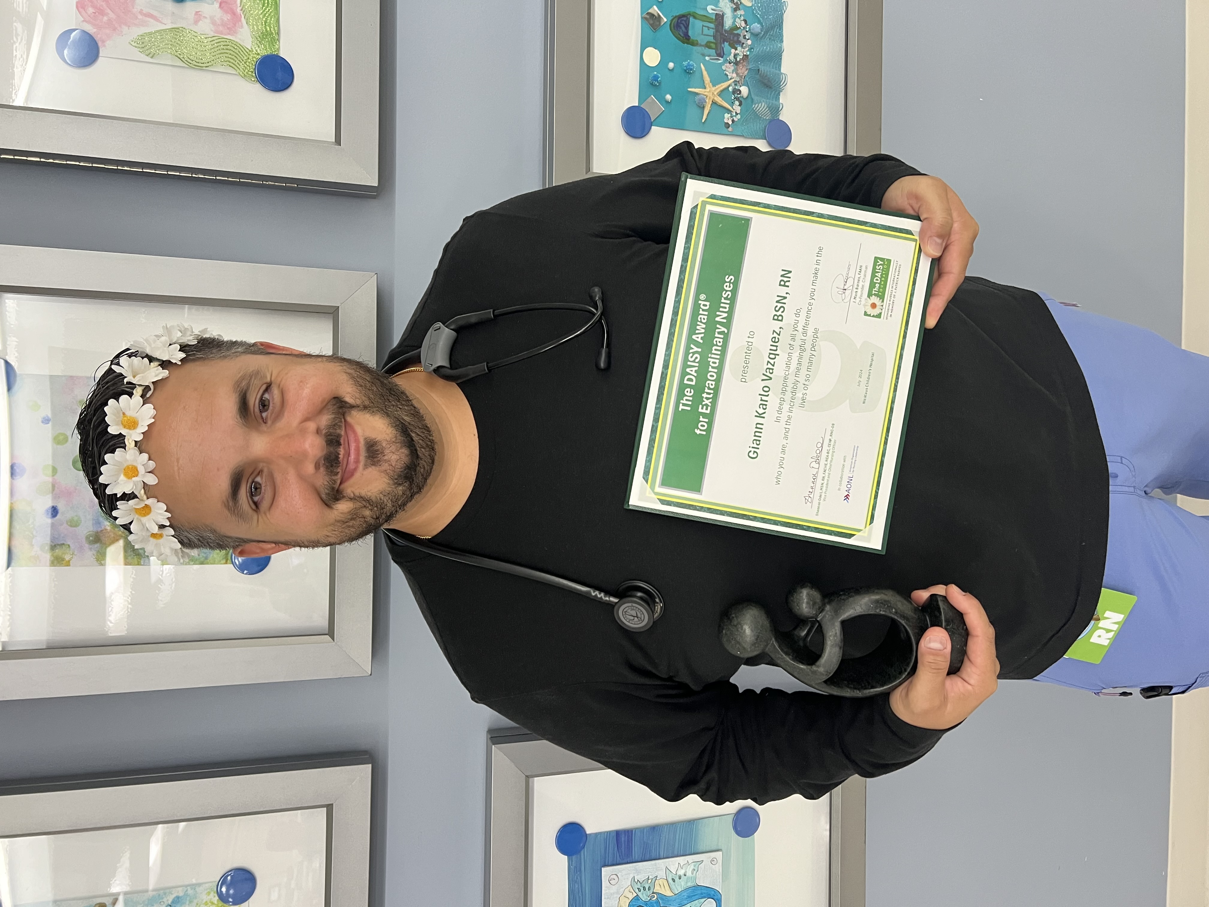 awardee wearing a headband of daisies, daisy award statue, and certificate.