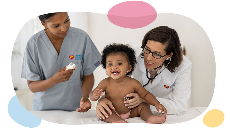female doctor and female nurse checking temperature of baby girl.