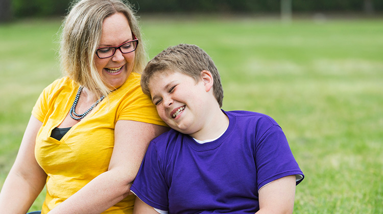 Overweight boy laughing and leaning towards his mom.
