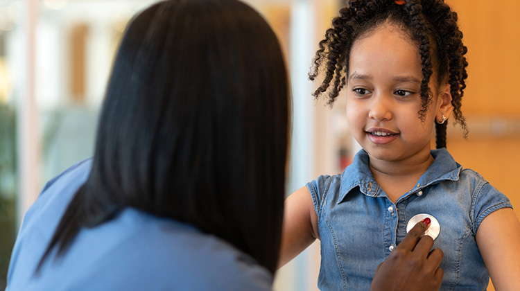 enfermera examina el corazón de una niña afro americana.