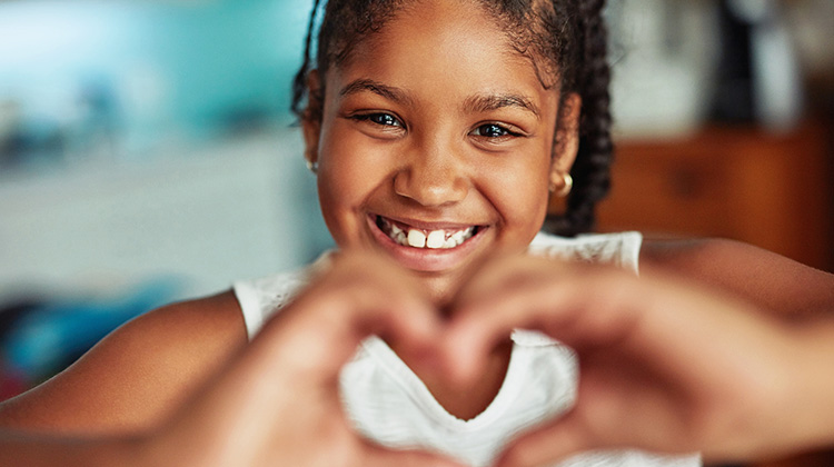 girl making a heart shape with her hands.