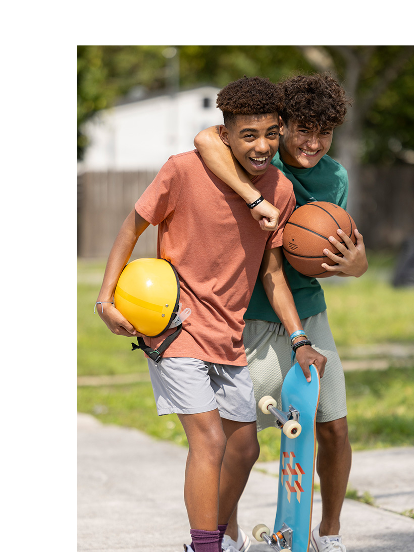 two teenage boys smiling as they do sports outside.