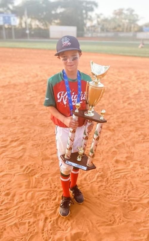 Krue con el trofeo de la serie mundial de béisbol juvenil