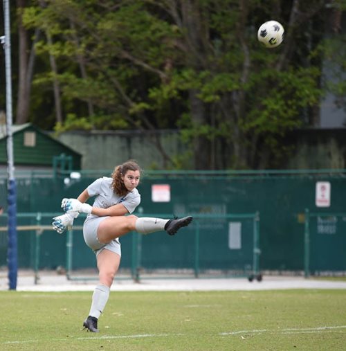 Stephanie kicking a soccer ball in a game.
